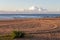 Calm morning at empty beach with a car tyre prints on sand, with sea and clouds at the background