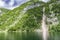 Calm mountain lake reflection, cloudy sky and pine tree cliffs. Tranquil alpine