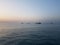 Calm ocean with blue sky and small boats and offshore ships