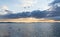 Calm ocean waters under an expressive sky at sunset with mountain silhouette in the background and buoys in the foreground