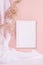 Calm pastel interior with white decoration - blank frame for poster, text or design hanging on pink wall, fluffy reeds, curtain.