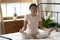 Calm peaceful Asian young woman meditating in bedroom alone