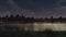 Calm pond in a city park under dark night sky