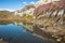 Calm pond reflecting multi-colored rock of red, purple and white