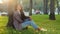 Calm relaxed young business woman beautiful girl with long curly hair brunette lady female resting sitting near tree in