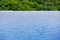 Calm and relaxing blue water flat surface of infinity pool with trees in background