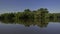 Calm river clear blue sky, forest and soaring balloon