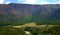 A calm river flowing through a valley on the banks of a pine forest at the foot of high mountains