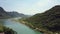 Calm river runs between mountain with road and fields aerial