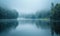 A calm riverside scene with fog rolling over the water in the early morning