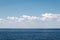 Calm sea on a background of blue sky with cloudsCalm sea against blue sky with clouds. Harmony of sea elements. Seascape. Copy