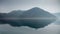 Calm sea or lake waves, rising morning fog and high blue mountains at sea coast