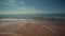 Calm sea with some waves breaking on the sandy beach. Summer sky with some trails from airplanes on the background