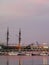 Calm sea water and sunset pink reflections on the harbor. Water landscape with boats