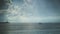 Calm seascape view with silhouettes of a line of buoys and a lighthouse under a beautiful cloudscape