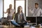 Calm serene employee meditating in office ignoring annoying coll