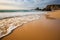 calm and serene golden beach, with waves rolling gently onto shore