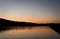 Calm, serene pond water reflects golden dusk light