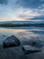 Calm, serenity, meditation concept. Sunset on the lake, stones in the water in the foreground, quiet water, cloudless sky