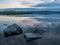 Calm, serenity, meditation concept. Sunset on the lake, stones in the water in the foreground, quiet water, cloudless sky