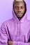 Calm serious black male in casual purple pullover looks at camera