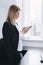 Calm serious young attractive blonde uses phone near table in office