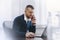 Calm serious young man uses phone while working at table in office