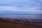 Calm shallow sea, rocky beach and dark sky, Northern Sea, Holkham beach, United Kingdom