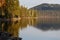 Calm shoreline of alpine lake with reflections of forest and mountains