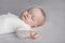 Calm silent adorable baby in white bodysuit sleeping on bed