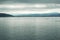 A calm silver ocean, with mountains in the background.