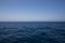 Calm smooth seawater surface under a blue almost cloudless sky