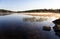 Calm sunrise morning at Swan Lake in Maine with fog on the surface on a late spring day