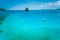 Calm turquoise sea surface with rocky island and white native banca boat. El Nido Marine Reserve Park