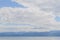 calm undulating water of Lake Baikal, blue mountains on the horizon, white soft clouds background
