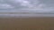 Calm wave coming towards the camera view while it moves away from it in a lonely beach during a cloudy day