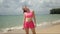 Calm woman in pink sportswear stretching neck on beach