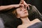 Calm woman receiving facial massage in a beauty salon by fingers