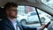 Calm young man in glasses driving along the street on the car and looking at the road. Side view. Transport, business