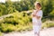 Calm young meditating woman standing on nature with closed eyes holding crossed hands in yoga mudra.