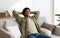 Calm young teen guy relaxing on sofa, napping with closed eyes, feeling peaceful at home, panorama