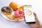 Calories counting and food control concept. woman using Calorie counter application on her smartphone with doughnut ,snack