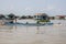 Cambodia, Tonle Sap Lake, February 2012: Fishermen sail on a boat against the backdrop of huts on the water. Life of the