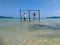 Cambodian Asian Man & Woman Standing on Swings in the Ocean