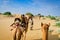 Camel caravan going through the sand dunes in desert