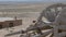 A camel stands at an old hut in the desert, an ancient cart.