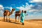 Cameleer camel driver with camels in dunes of Thar