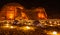 Camels laying in front of ancient tombs of Hegra city illuminated during the night, Al Ula