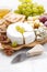 Camembert, grapes and crackers on a white table, vertical