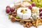 Camembert, grapes and snacks on a white table, closeup